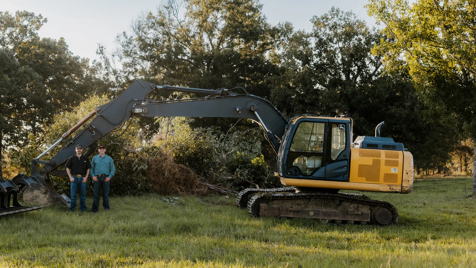 Compact track loader working a brushy tree line on rural acreage